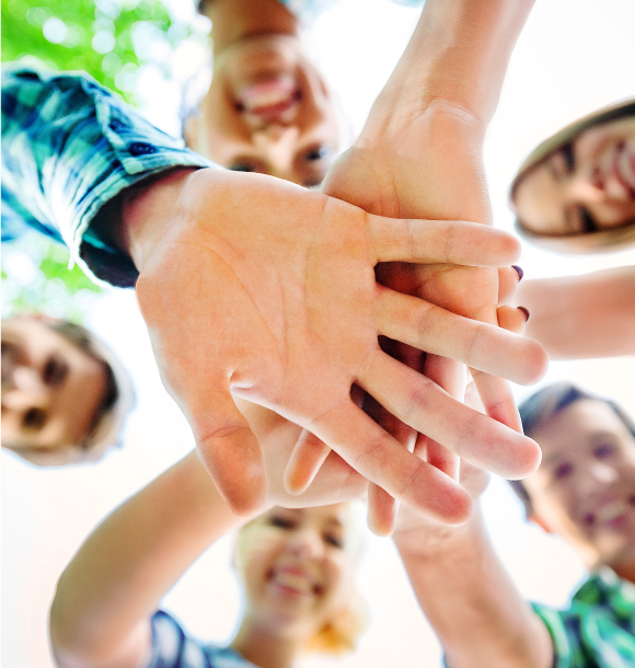 Students standing in a circle with hands on top of each other